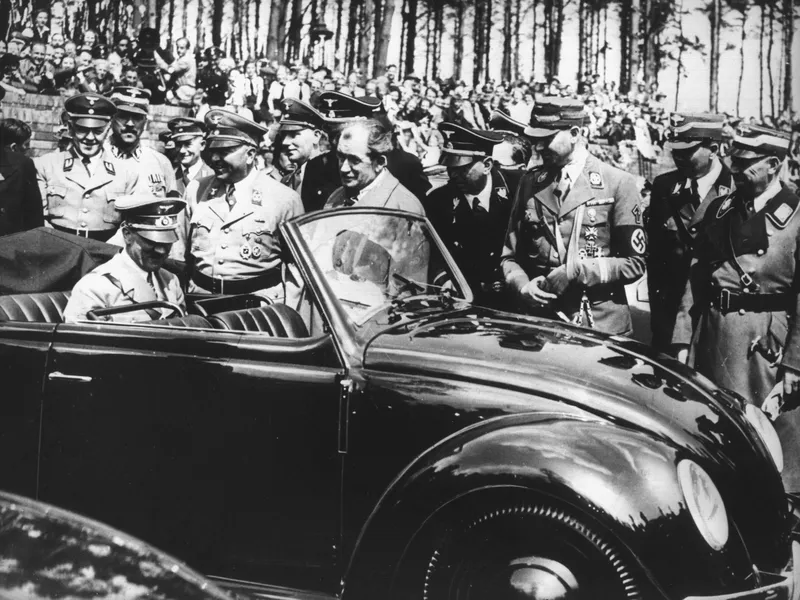 Kuvassa Ferdinand Porsche ja Adolf Hitler juttelevat maaliskuussa 1938. Hitler istuu Volkswagen Typ 1:ssa, ”kansanautossa”. Kuplavolkkareita valmistettiin yli 21 miljoonaa kappaletta vuosina 1938–2003.