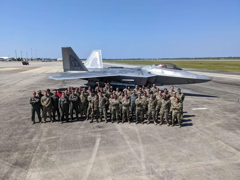 Ennätyksen saavuttanut joukko lentäjiä ja tukihenkilökuntaa poseeraa Tyndallin lentotukikohdassa F-22-koneen edessä syyskuussa 2022.