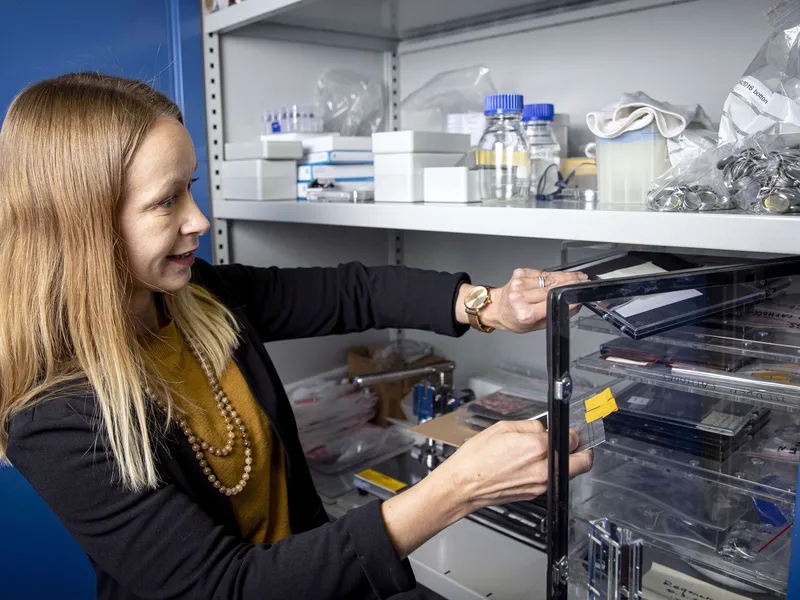 Marja Vilkman tutkii laboratoriokaappia, jossa säilytetään akkumateriaaleja. Kuva lokakuulta 2022.