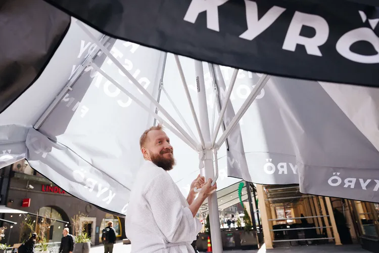 Kyrö Distilleryn perustajiin kuuluva Mikko Koskinen sulki kovan tuulen takia aurinkosuojaa Keskuskadulla Helsingissä tiistaina.