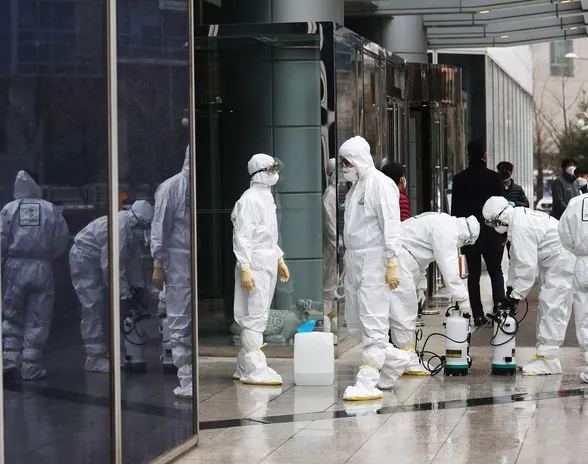 Suojapukuihin pukeutuneet työntekijät desinfioivat rakennusta Etelä-Koreassa ehkäistäkseen koronavirusta.