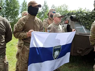 Eilen keskiviikkona otetussa kuvassa taistelijat esittelevät Vapaan Venäjän legioona -ryhmän lippua Pohjois-Ukrainassa.