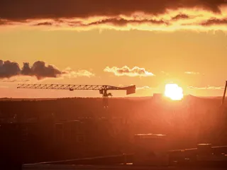 Aurinko laski rakennustelineiden ylle Espoossa.