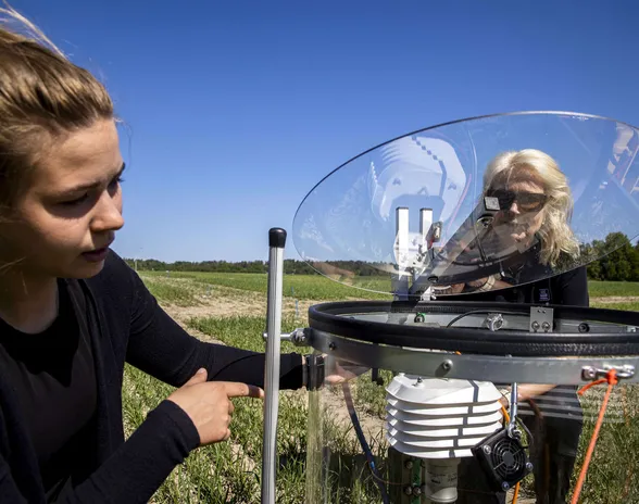Yaran vanhempi kehitysagronomi Mervi Seppänen (oik.) ja Datasensen tutkimusinsinööriharjoittelija Saara Somerikko asentavat kevätvehnäpellolle CO₂-mittakammiota.