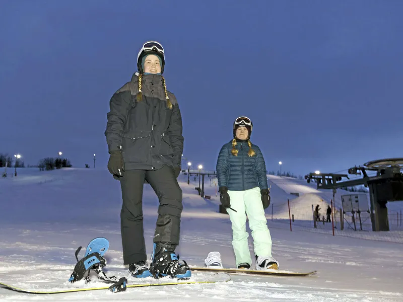 Jenni Louhimo ja Sanni Niskanen harjoittelevat lumilautailua Ruskotunturilla lähellä Oulun kaupunkia.