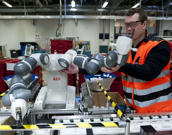 Koneturvallisuusasiantuntija Ville Linna asettelee YuMi-robotin käsiä manuaalisesti toivottuun asentoon.