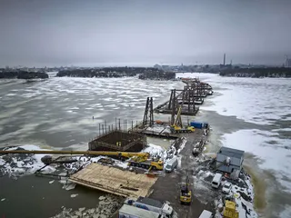 Työsilta päättyy pylonin rakennuspaikan vierelle rakennettuun tekosaareen. Korkeasaaren puolelta tulee toinen työsilta, väliin jää aukko veneilijöitä varten.
